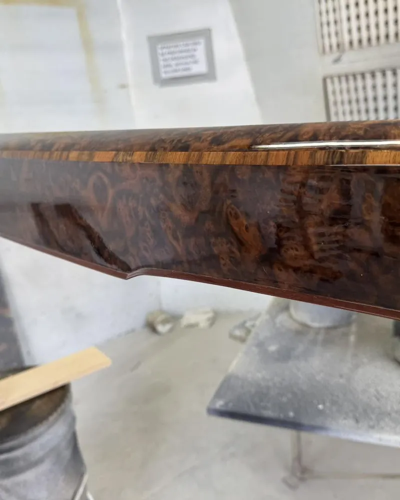 Close view of a French polished burr walnut table edge with a deep mirror finish