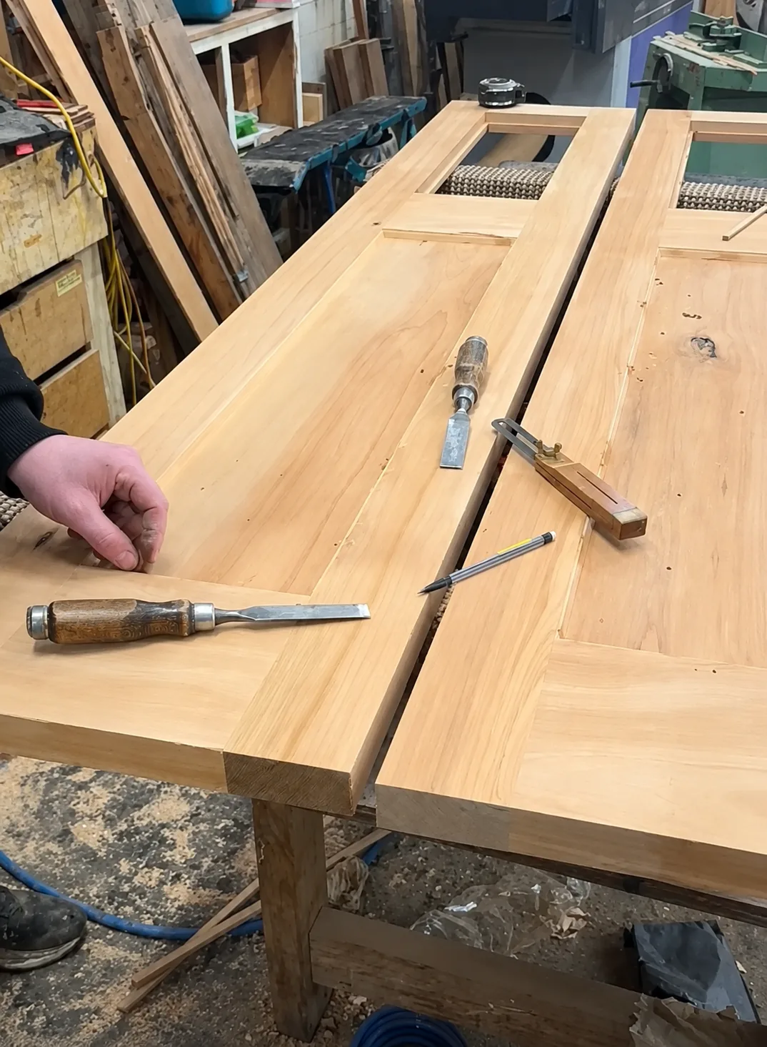 A solid timber door on the bench at D.J. Morrison with chisels, a marking gauge and a pencil