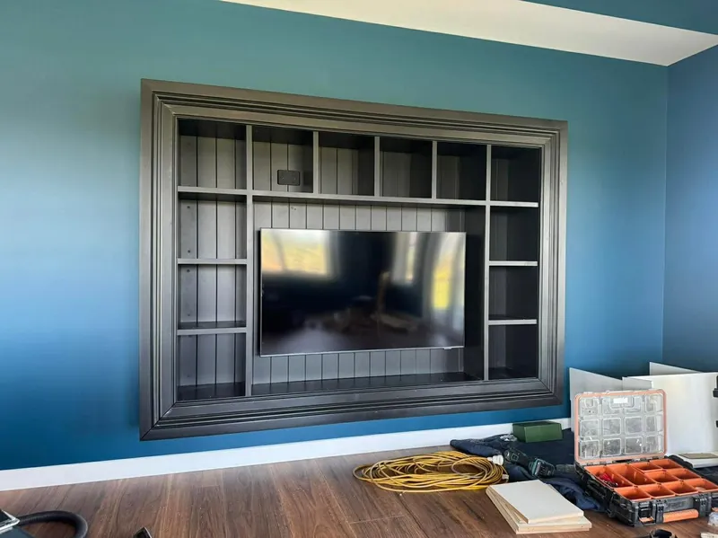 Built in media wall with shelving and panelled surround in a dark painted finish
