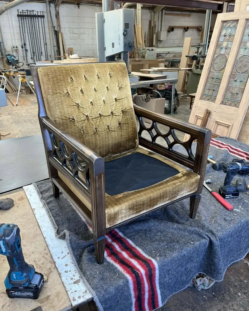 Armchair before restoration with worn gold velvet upholstery in the workshop